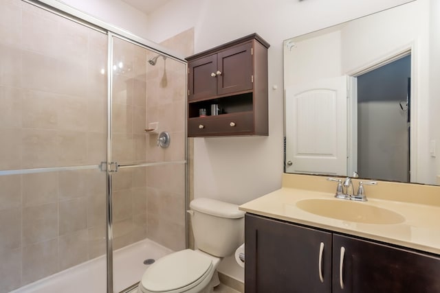 bathroom with toilet, vanity, and a shower with door