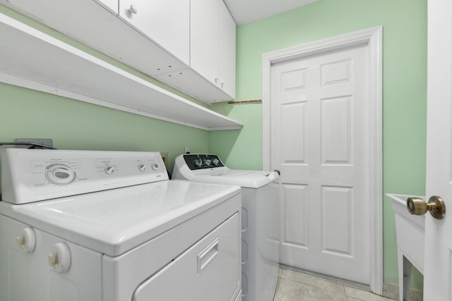 clothes washing area with cabinets, light tile patterned floors, and independent washer and dryer