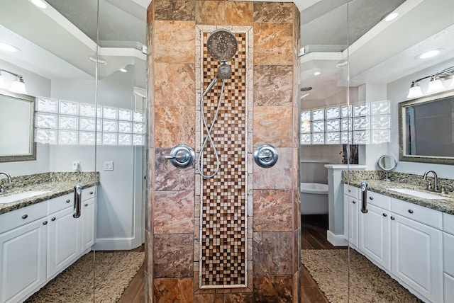 bathroom with tiled shower and vanity