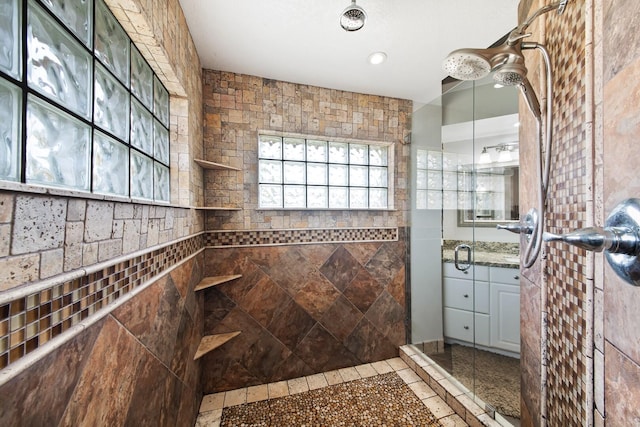 bathroom with a tile shower and vanity