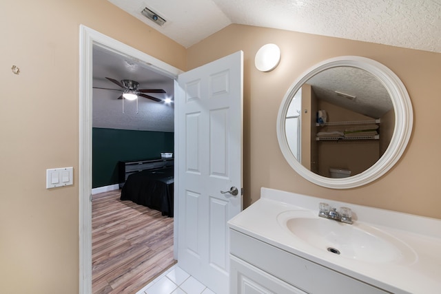 bathroom with ceiling fan, lofted ceiling, vanity, and a textured ceiling