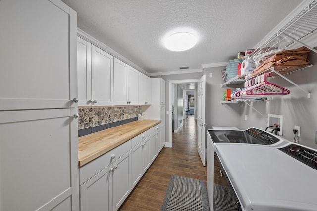 kitchen with crown molding, washing machine and dryer, tasteful backsplash, white cabinets, and a textured ceiling