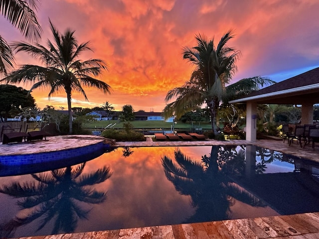 pool at dusk with a patio area