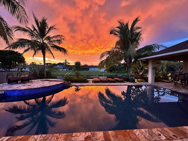 pool at dusk featuring a patio