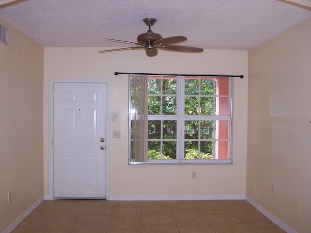 entrance foyer with ceiling fan, a textured ceiling, and tile patterned floors