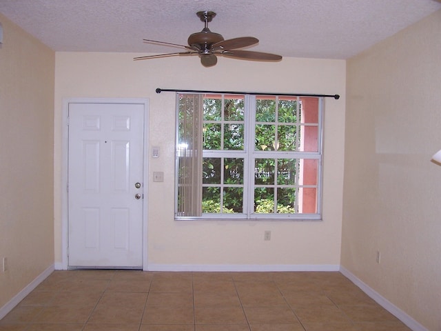 tiled foyer entrance with a textured ceiling and ceiling fan