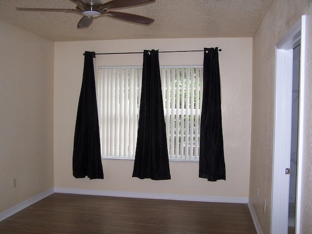 unfurnished room with ceiling fan, dark wood-type flooring, and a textured ceiling