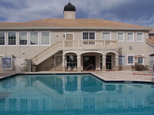 back of property featuring a community pool and a patio