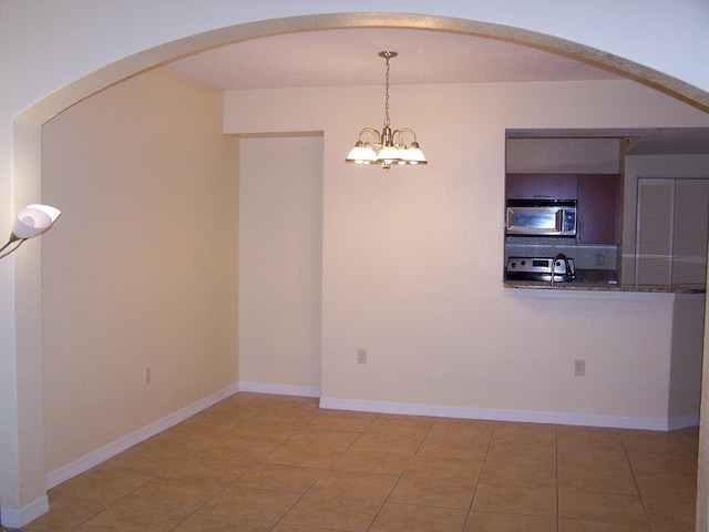 tiled empty room with an inviting chandelier