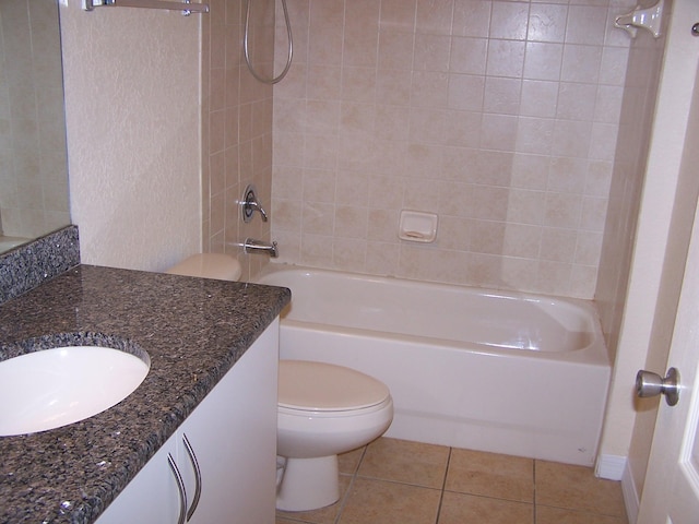 full bathroom featuring toilet, vanity, tiled shower / bath, and tile patterned flooring