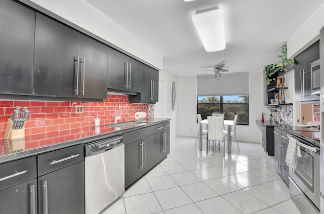 kitchen featuring stainless steel appliances, dark stone counters, tasteful backsplash, sink, and ceiling fan