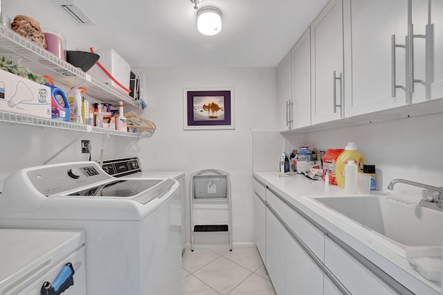 laundry room featuring cabinets, separate washer and dryer, light tile patterned floors, and sink