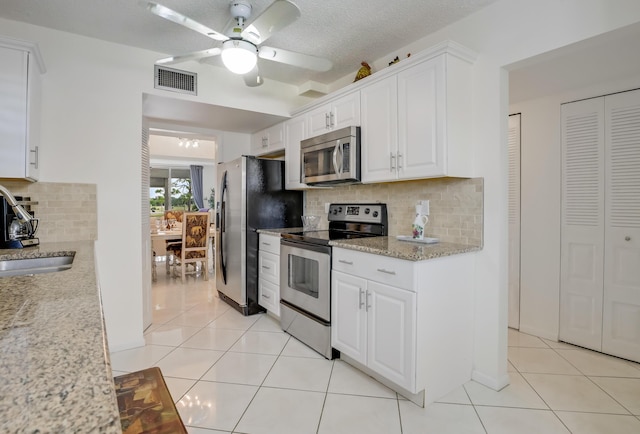 kitchen featuring ceiling fan, backsplash, light tile patterned floors, appliances with stainless steel finishes, and white cabinets