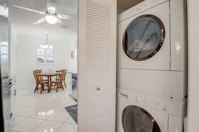 clothes washing area featuring stacked washer and dryer, light tile patterned floors, and ceiling fan with notable chandelier