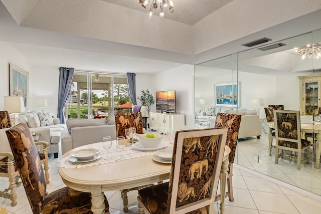 dining room featuring light tile patterned floors, a textured ceiling, a tray ceiling, and a notable chandelier