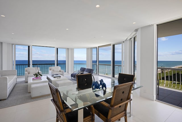 dining space with light tile patterned floors, a water view, and expansive windows