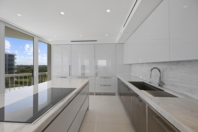 kitchen with white cabinetry, tasteful backsplash, sink, light tile patterned floors, and black electric cooktop