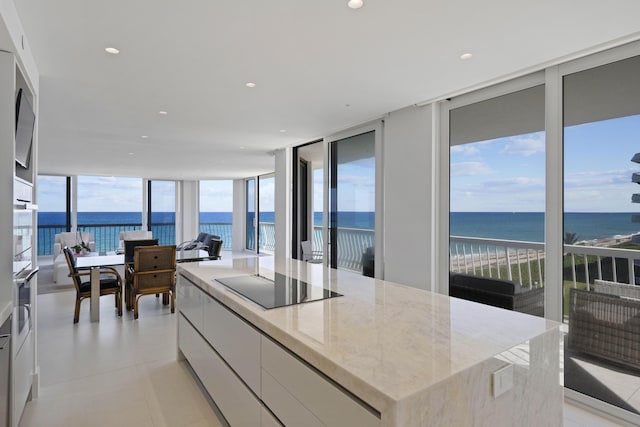 kitchen with a water view, floor to ceiling windows, black electric cooktop, and white cabinetry