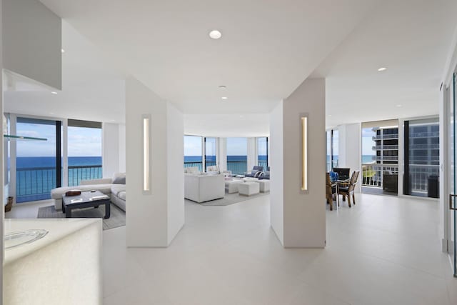 corridor featuring a water view, a wall of windows, and light tile patterned floors