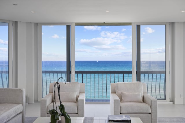 living room with expansive windows, a water view, and a healthy amount of sunlight