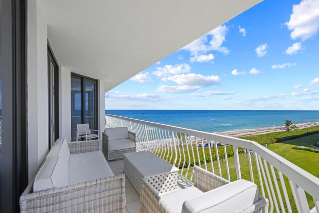 balcony featuring an outdoor hangout area, a water view, and a beach view