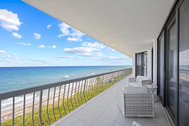 balcony with a water view and a view of the beach