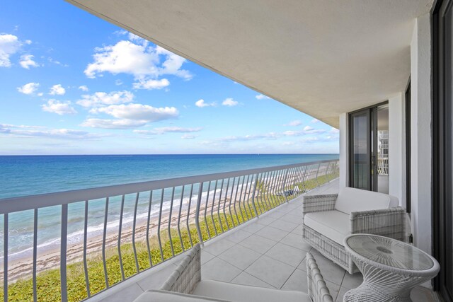 balcony featuring a view of the beach and a water view