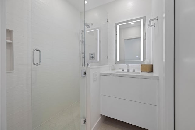 bathroom featuring a shower with door and vanity