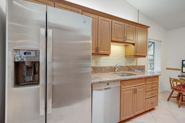 kitchen featuring dishwashing machine, sink, stainless steel fridge, vaulted ceiling, and light stone counters