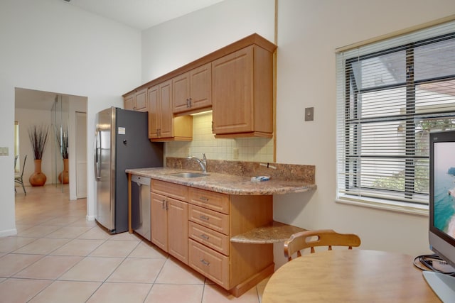 kitchen with light tile patterned flooring, a sink, stainless steel dishwasher, decorative backsplash, and light stone countertops