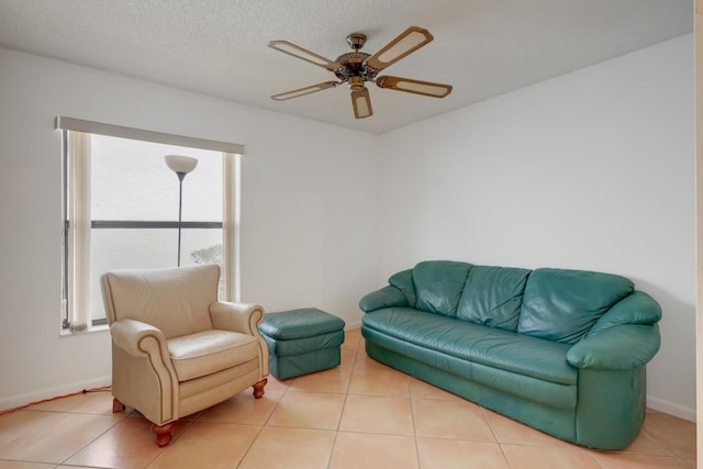 tiled living area featuring a textured ceiling, a ceiling fan, and baseboards