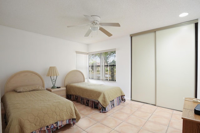 bedroom with a textured ceiling, ceiling fan, light tile patterned floors, recessed lighting, and a closet