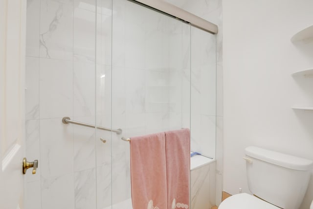 full bathroom with a tile shower and toilet