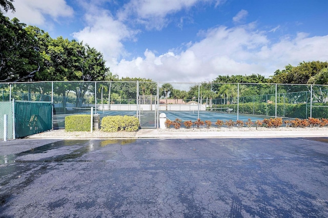 surrounding community featuring a gate, a tennis court, and fence