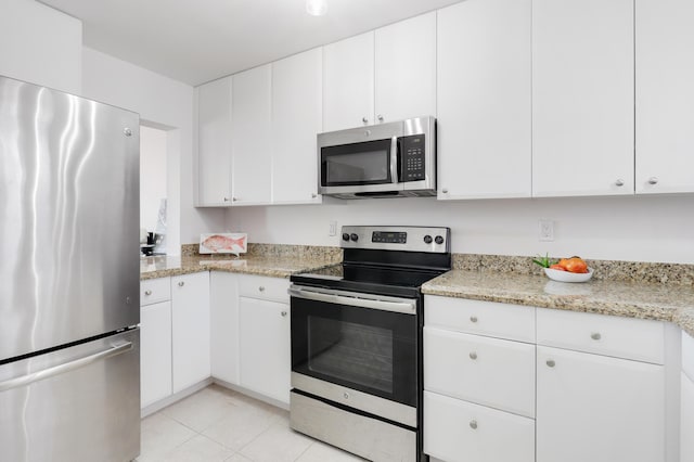 kitchen featuring light tile patterned floors, stainless steel appliances, white cabinetry, and light stone countertops