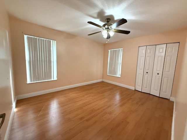 unfurnished bedroom featuring ceiling fan, light hardwood / wood-style floors, and a closet