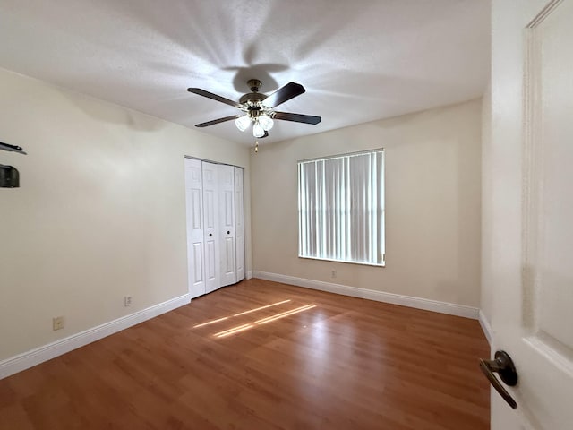 unfurnished bedroom featuring ceiling fan, a closet, and hardwood / wood-style flooring