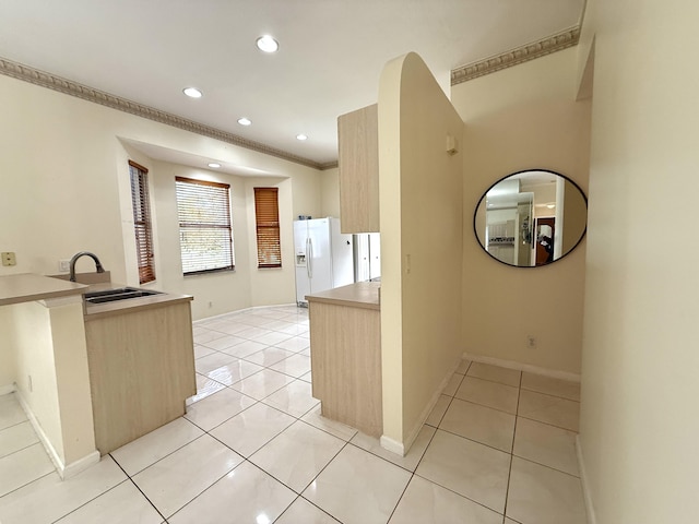 kitchen with light tile patterned floors, light brown cabinets, white refrigerator with ice dispenser, and ornamental molding