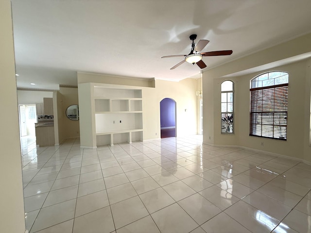 tiled spare room with ceiling fan, ornamental molding, and a healthy amount of sunlight