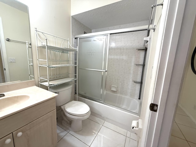 full bathroom featuring toilet, combined bath / shower with glass door, tile patterned flooring, a textured ceiling, and vanity