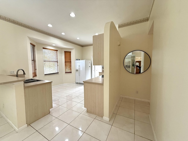 kitchen with sink, white refrigerator with ice dispenser, and light brown cabinets