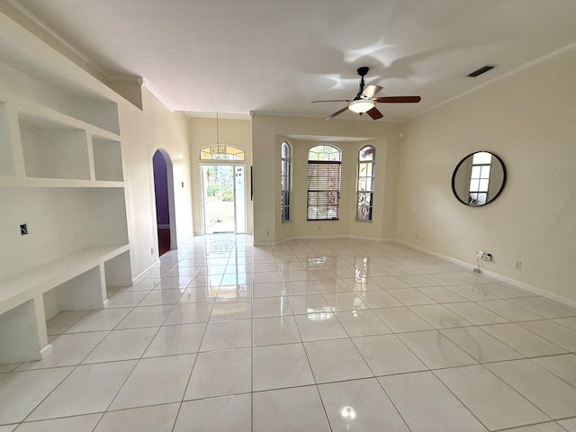 tiled empty room with ceiling fan, built in shelves, and ornamental molding