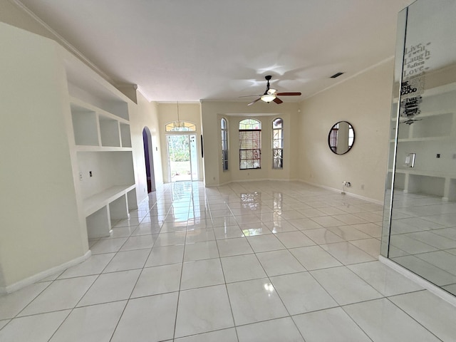 spare room with ceiling fan, light tile patterned floors, crown molding, and built in shelves