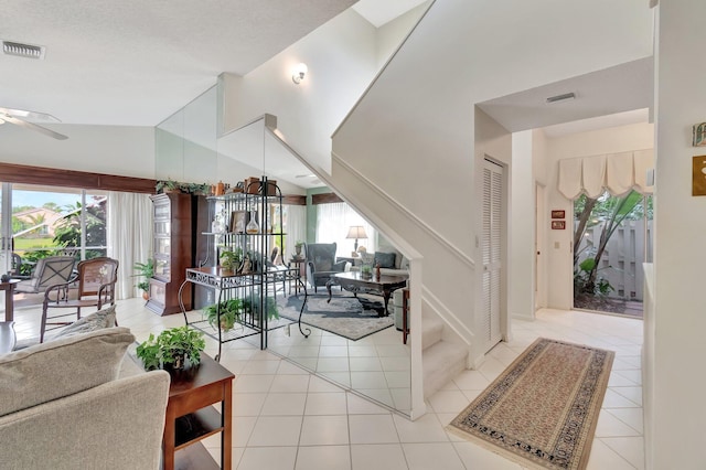 interior space featuring ceiling fan, light tile patterned floors, and vaulted ceiling