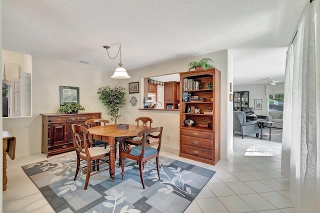 dining space with a textured ceiling, ceiling fan, and light tile patterned floors