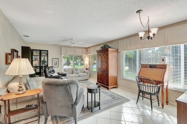 tiled living room featuring a textured ceiling, ceiling fan with notable chandelier, and plenty of natural light