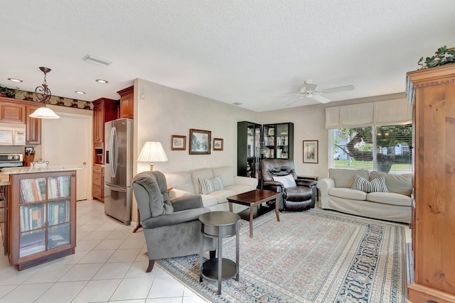 tiled living room with ceiling fan and a textured ceiling