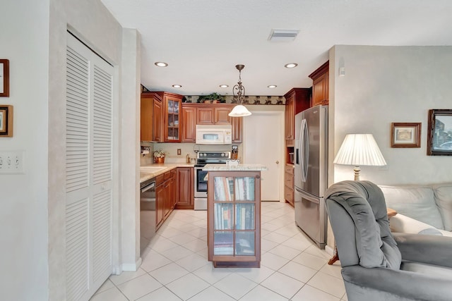 kitchen featuring light tile patterned floors, appliances with stainless steel finishes, hanging light fixtures, and a center island