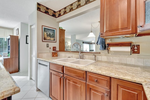 kitchen with light tile patterned floors, light stone countertops, a textured ceiling, stainless steel dishwasher, and sink