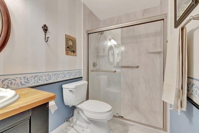 bathroom featuring tile patterned floors, toilet, a shower with door, and vanity